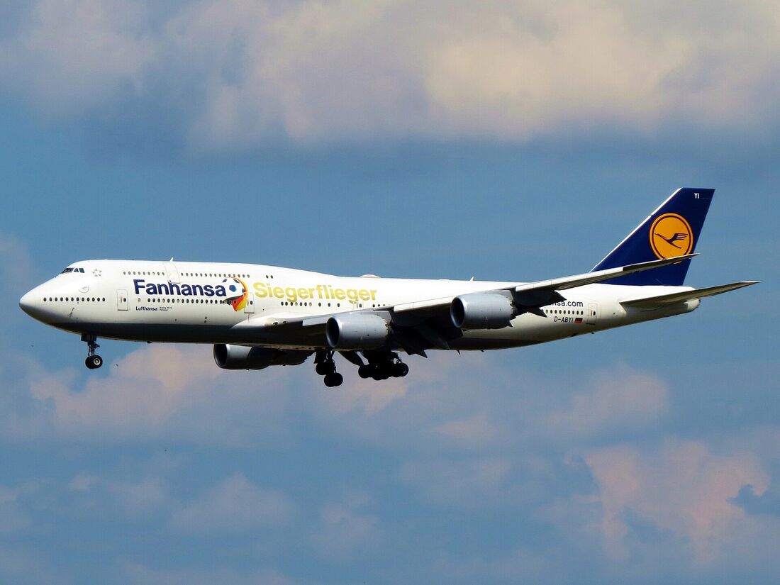 A Lufthansa Boeing 747-8 on approach seen from the side, its upper deck extending well back along the fuselage