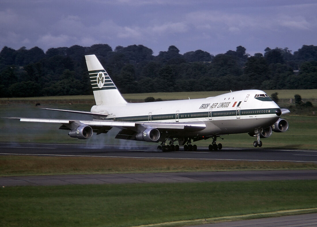 An Aer Lingus Boeing 747-100 in white livery touching down on a runway, seen from the side, with a short upper-deck hump behind the cockpit